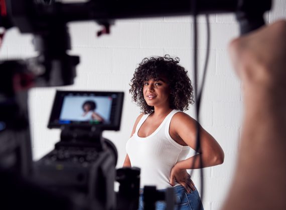 Female Model Posing For Video Camera On Film Set